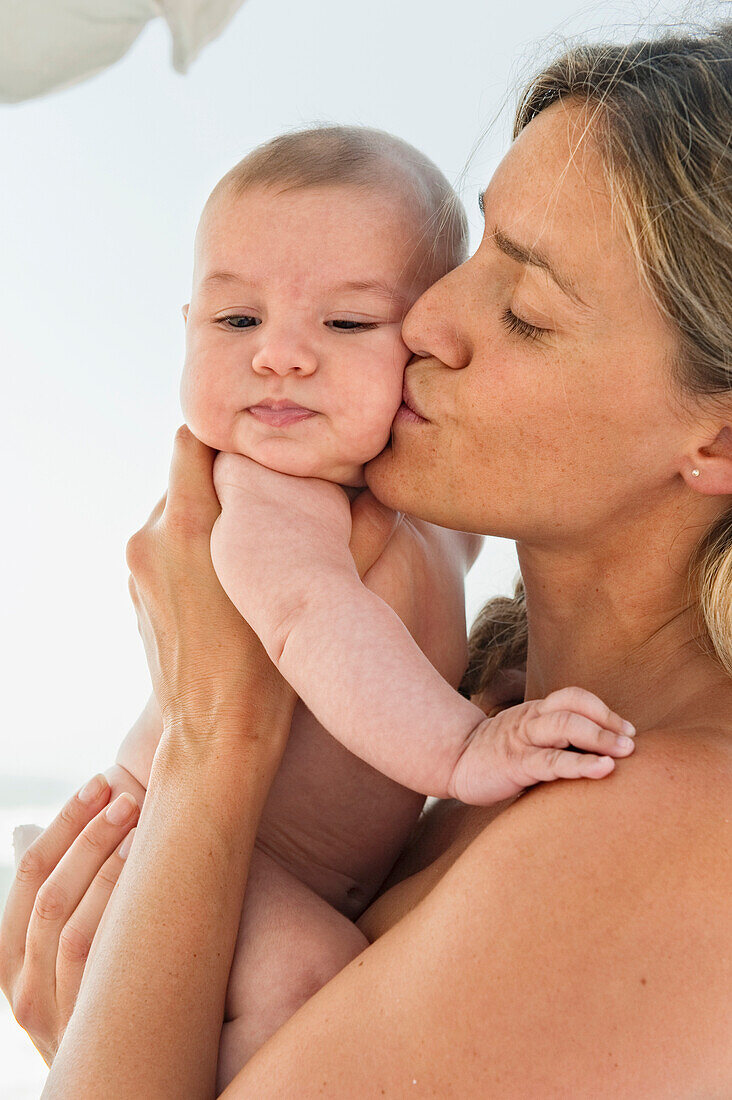 'A Mother Holds Her Baby Close With A Kiss; Banalmadena Costa, Malaga, Andalusia, Spain'