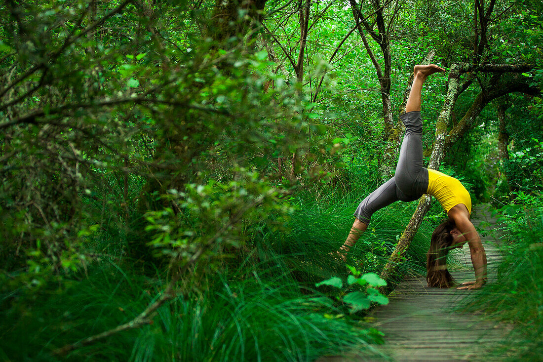 Woman practicing yoga in the forest, Landes, Hossegor