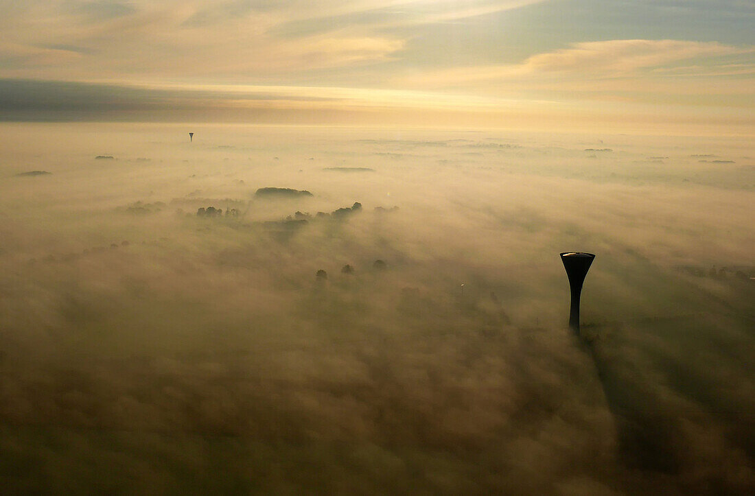 Aerial view above the fog. Emerge a first water tower in the foreground