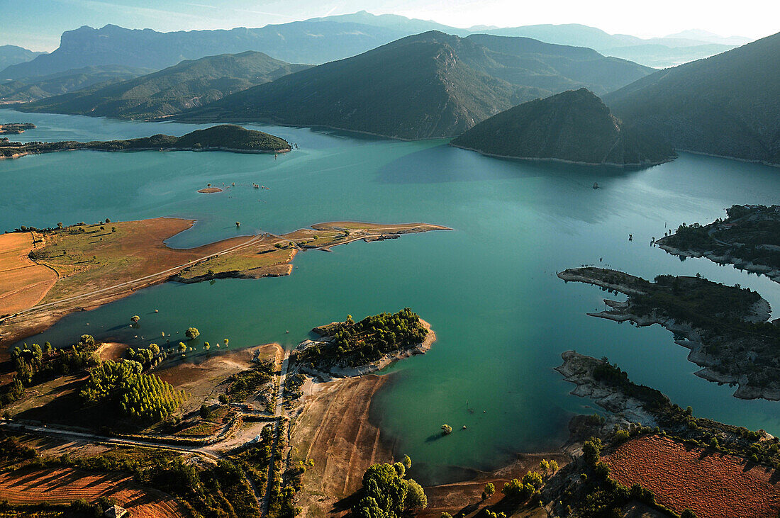 aerial view of a lake. Field and trees in the foreground. Mountain in the background