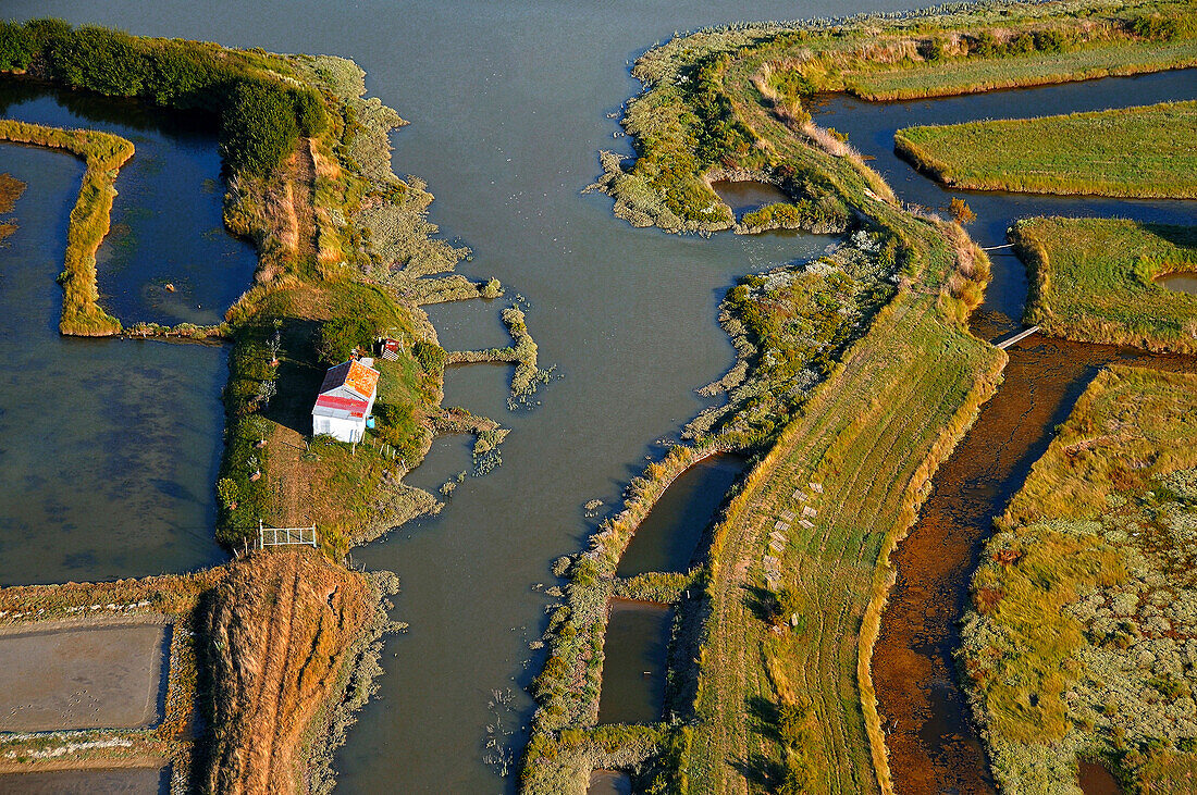 aerial view of the marsh crossed by a chanal. On the left a house