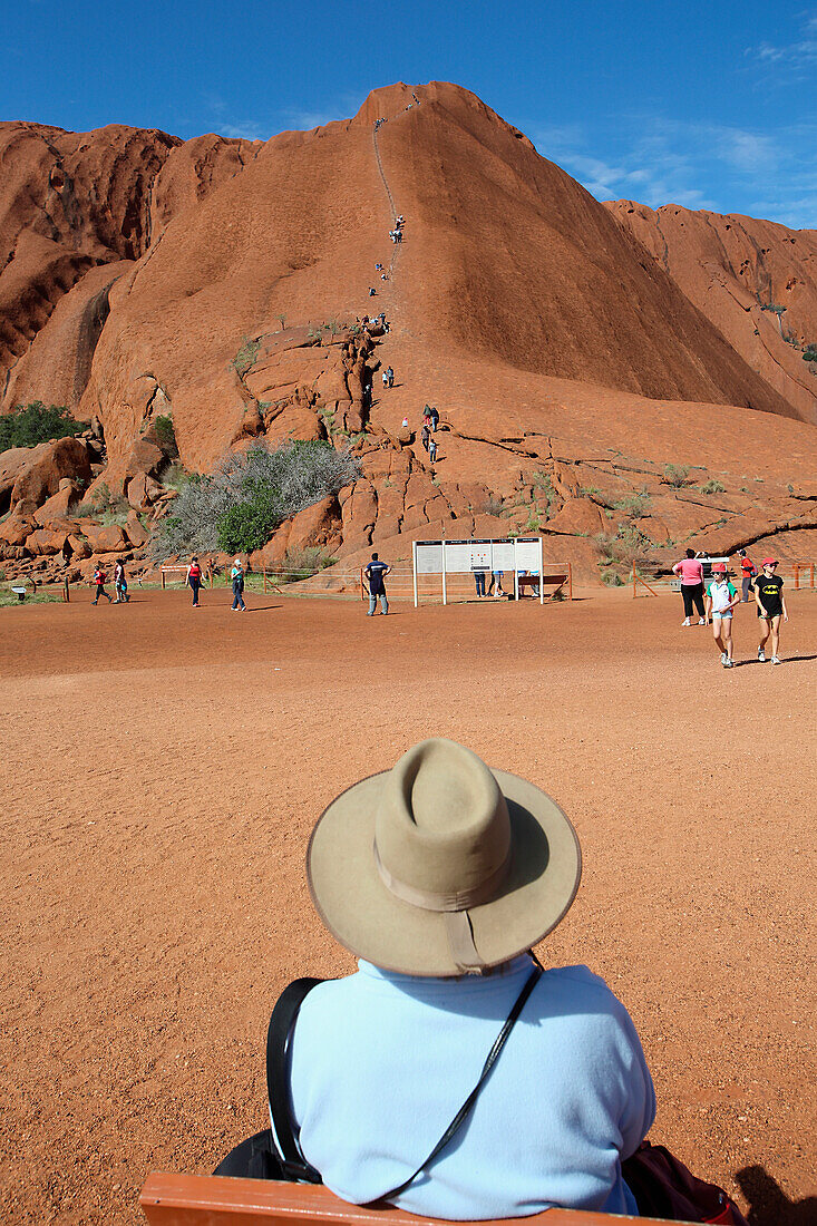 'Tourists watching people climb Uluru, formerly known as Ayers Rock; Northern Territory, Australia'