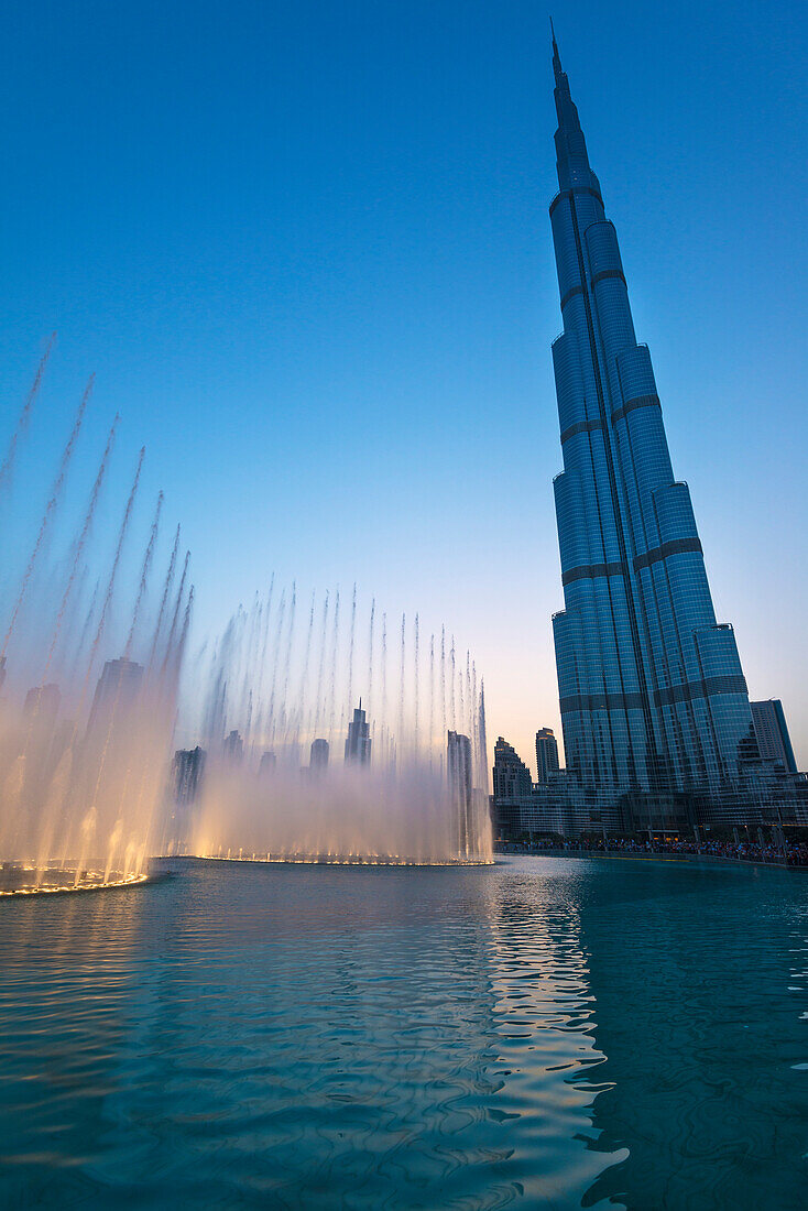 'Fountain display in front of the Burj Khalifa at sunset; Dubai, United Arab Emirates'