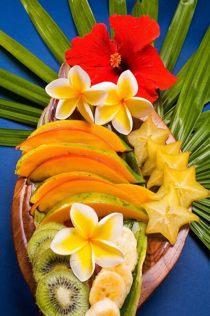 Studio Shot Pf A Variety Of Tropical Fruit Sliced On A Platter, With Flowers.
