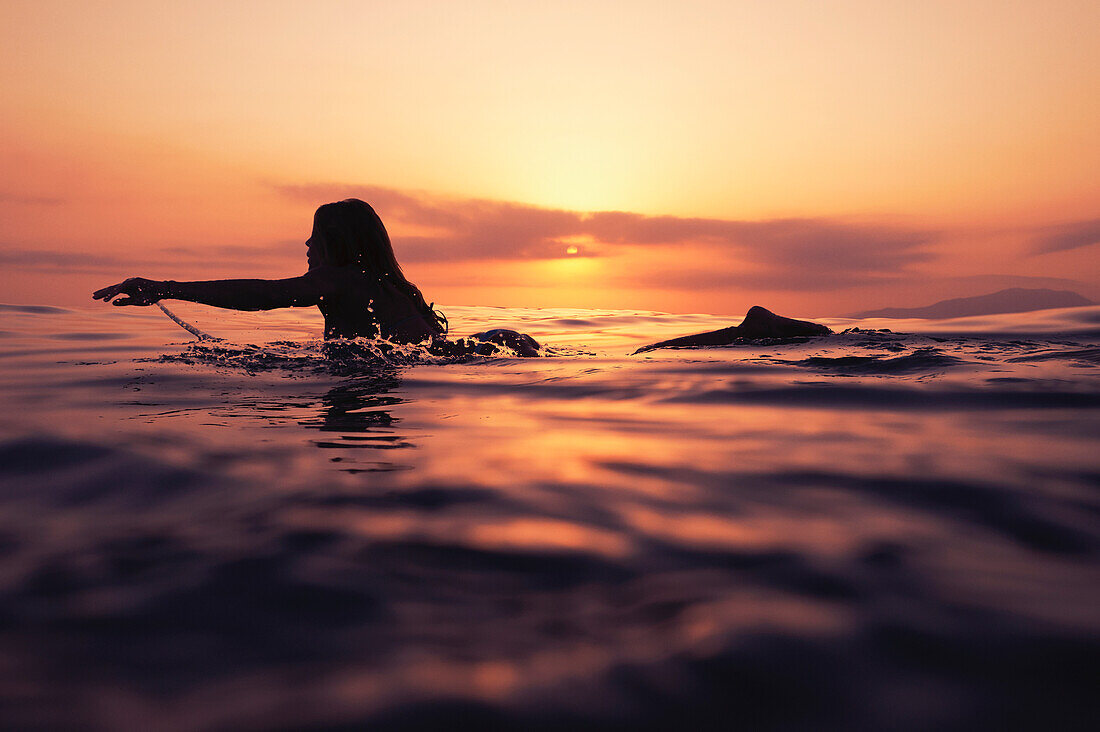 'A Woman Paddling On A Surfboard At Sunset; Tarifa, Cadiz, Andalusia, Spain'