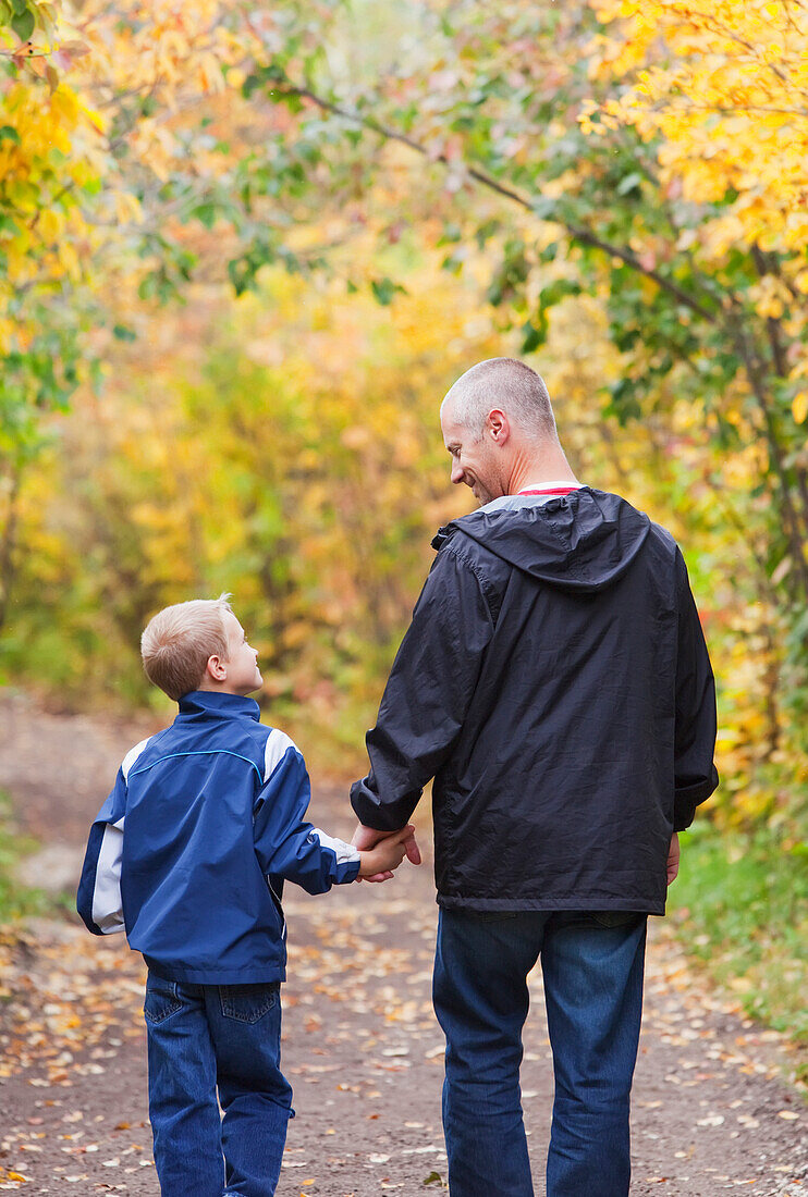 'Father And Son Walking On A Path In A Park In Autumn; Edmonton, Alberta, Canada'