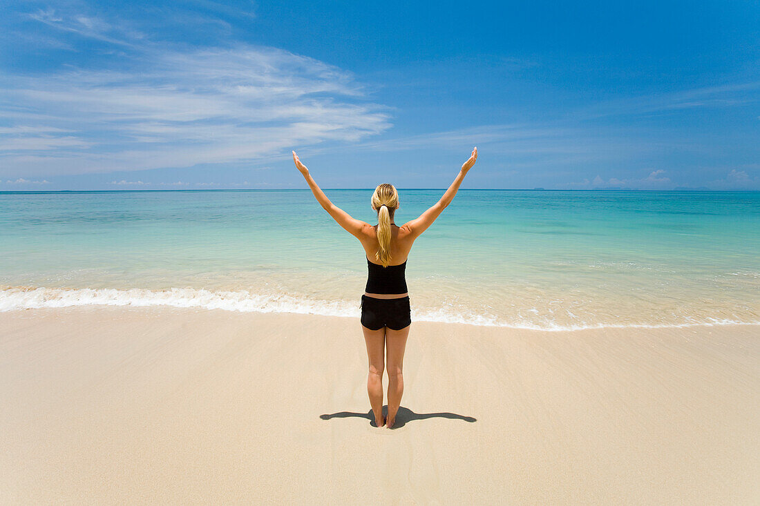 'A Woman Tourist Stands With Arms Raised On A Tropical Island; Koh Lanta, Thailand'