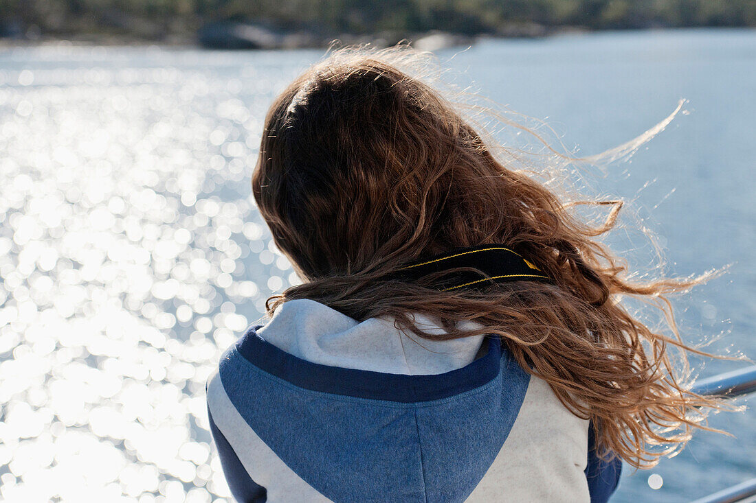 'A Girl's Hair Blowing In The Wind As She Stands At A Railing On The Water's Edge; Norway'