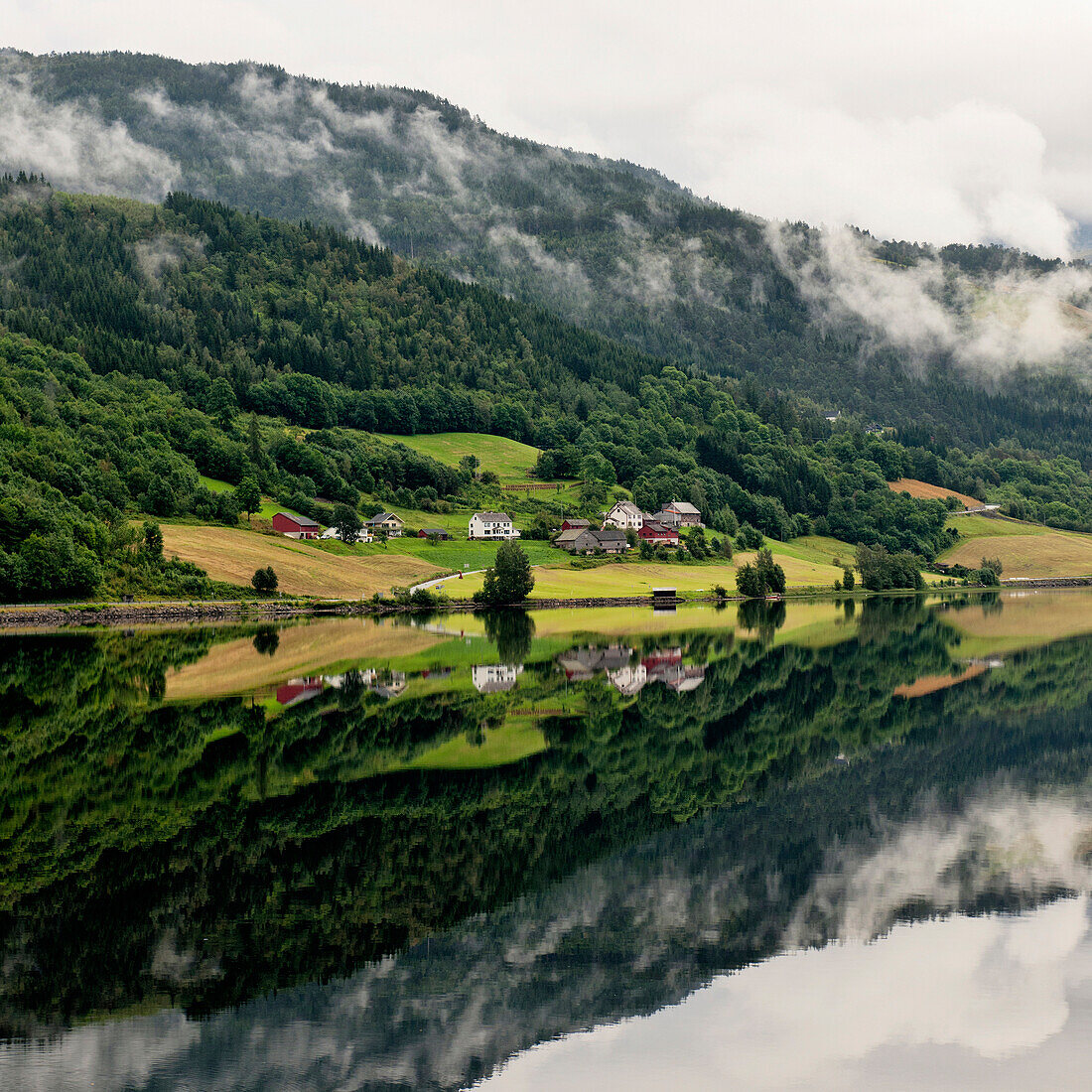 'Houses And A Forest On A Mountainside Reflected In Tranquil Water; Granvin, Norway'
