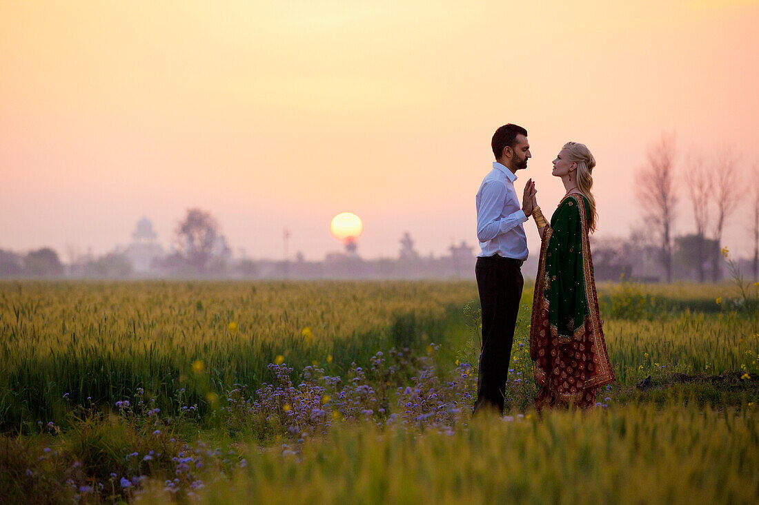 'A Couple Standing Face To Face In A Field At Sunset; Ludhiana, Punjab, India'