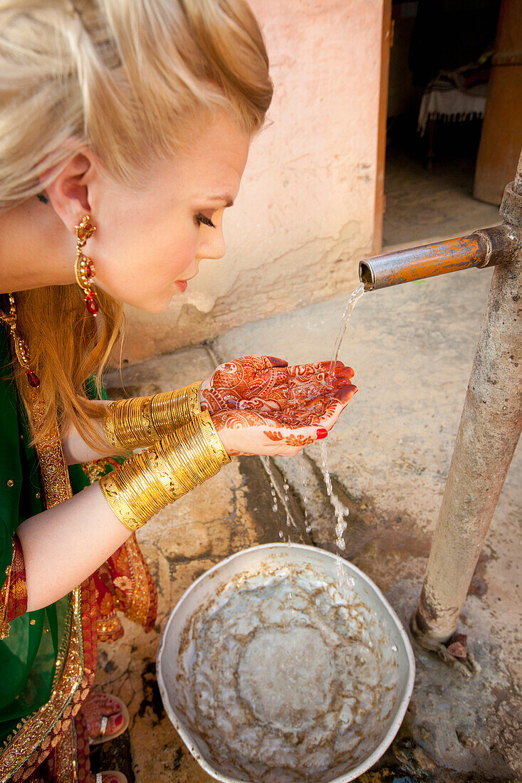'A Woman With Mehndi On Her Palms Cups Her Hands To Collect Water From A Tap; Ludhiana, Punjab, India'