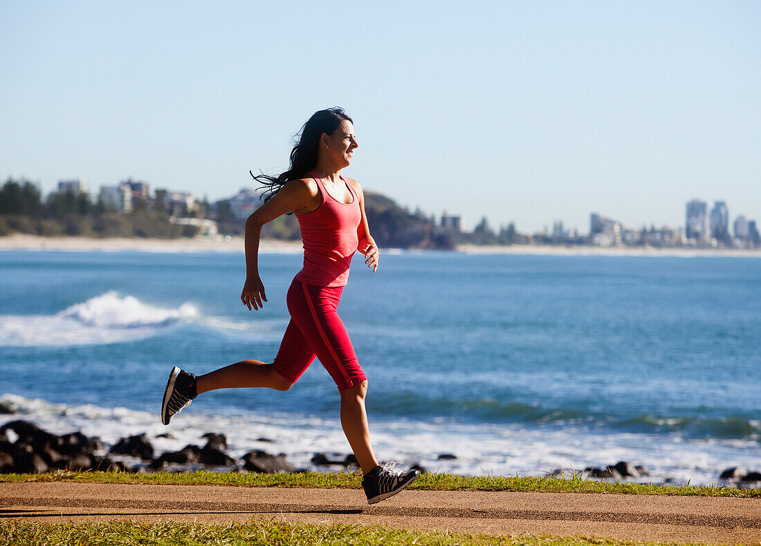 'A woman runs on a path along the water;Gold coast queensland australia'