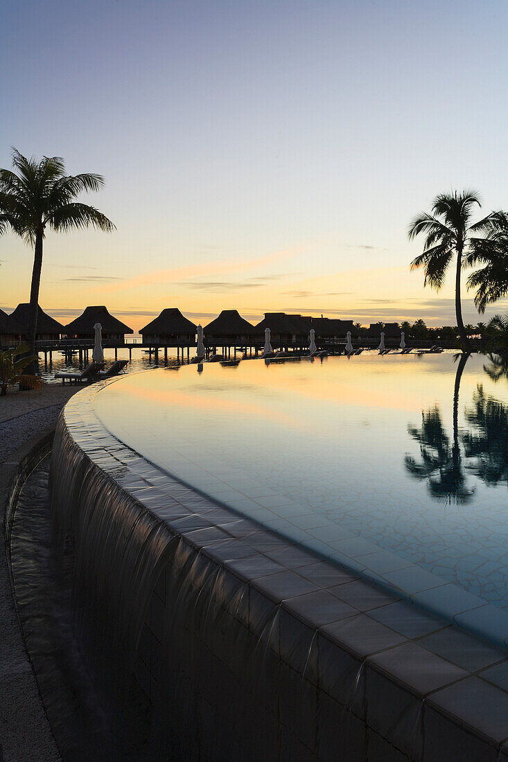 'Sunset and palm trees reflecting in a pool at the bora bora nui resort and spa;Bora bora island society islands french polynesia south pacific'