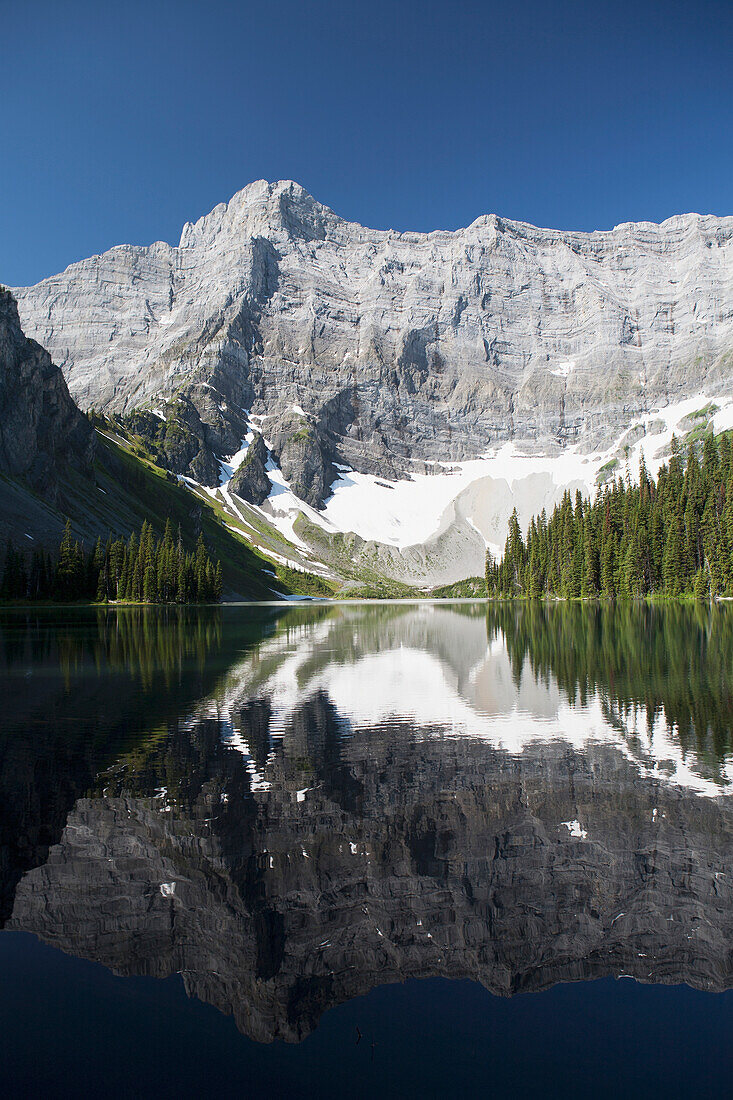 'Mountain reflecting in mountain lake with snow and blue sky in kananaskis provincial park;Alberta canada'