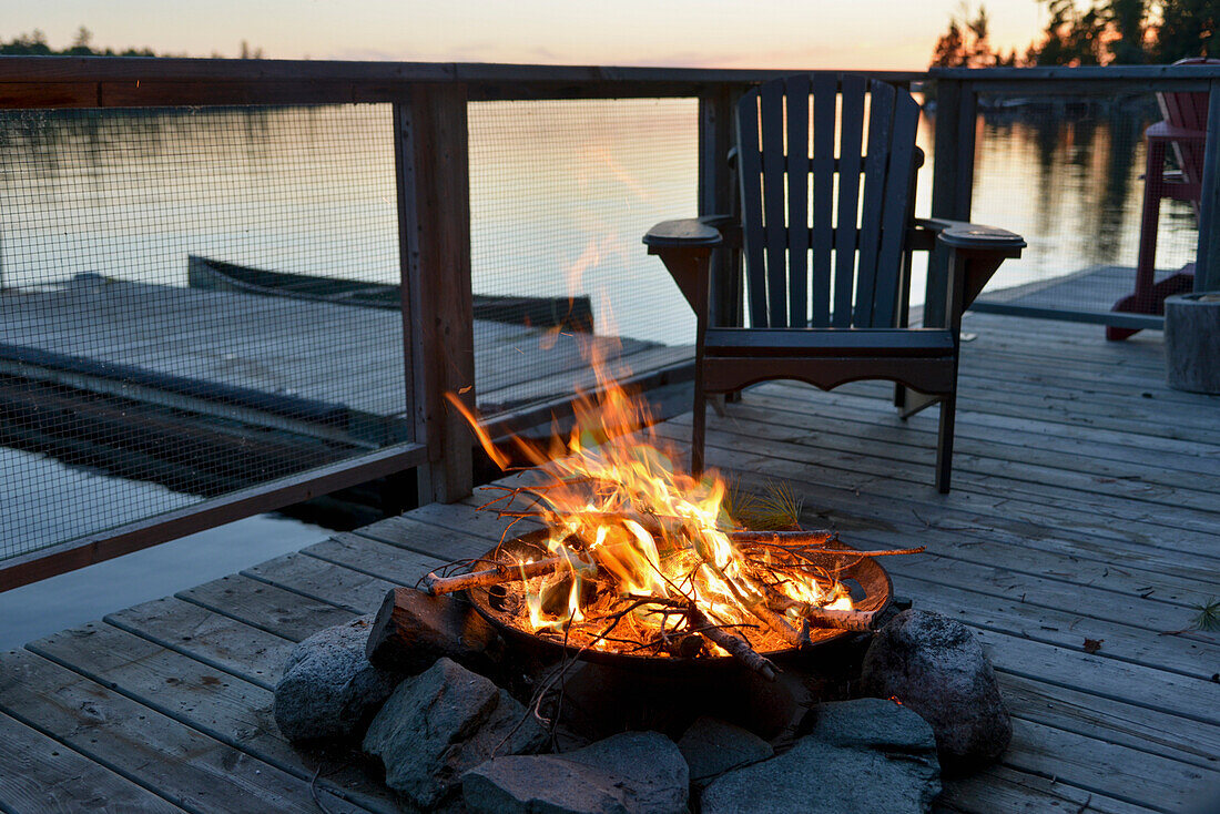 'Fire pit on a wooden dock on a lake at sunset;Lake of the woods ontario canada'
