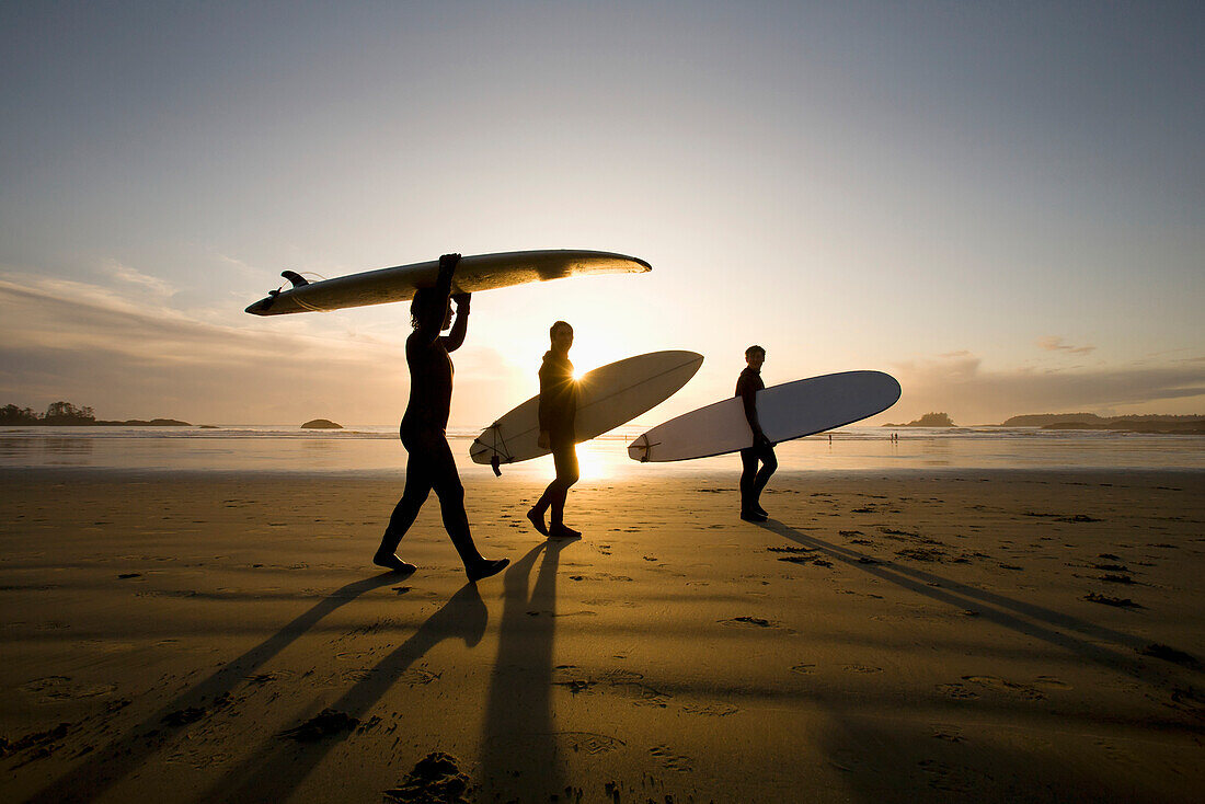 'Silhouette Of Three Surfers Carrying Surfboards; Chesterman Beach Tofino Vancouver Island British Columbia Canada'
