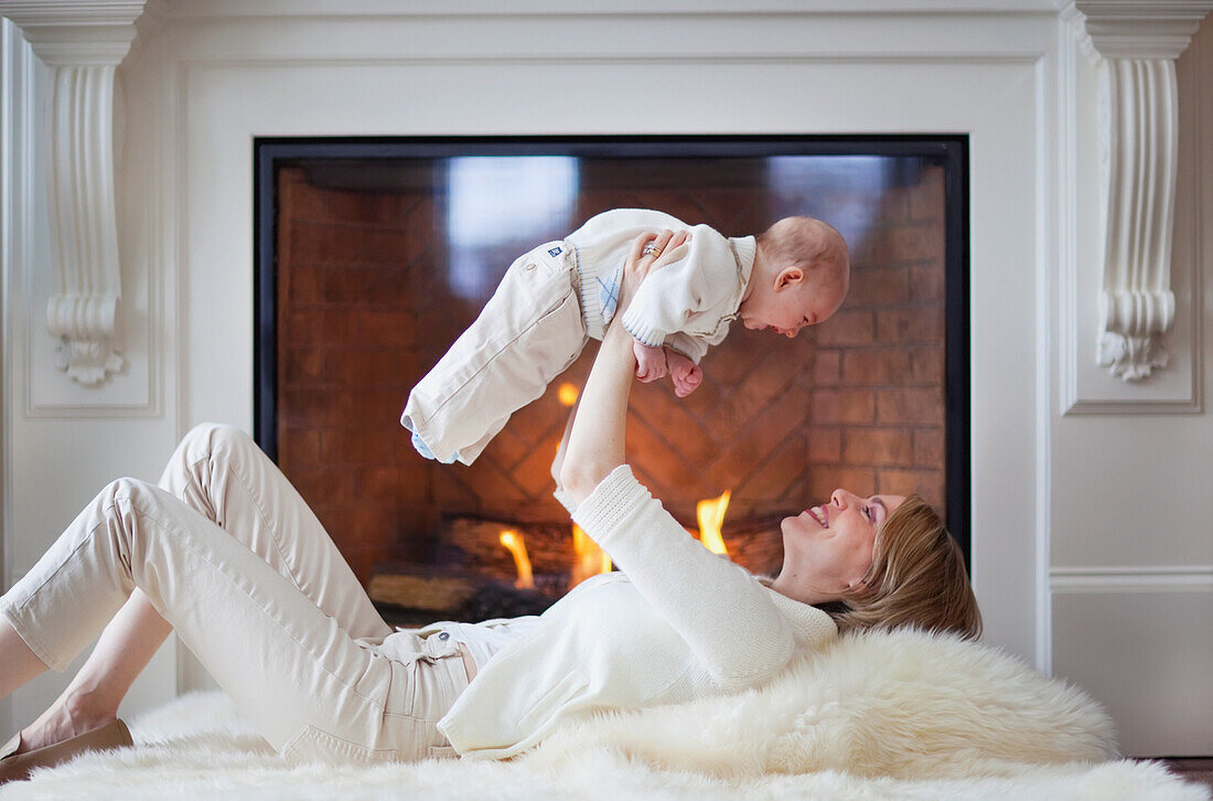 'Mother And Baby On Carpet In Front Of Fireplace; Jordan, Ontario, Canada'