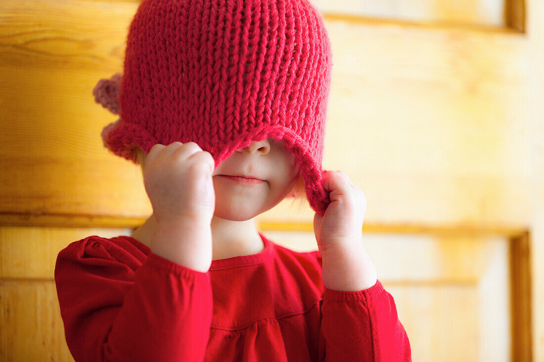 'A Child Pulling A Hat Over Her Eyes; Spruce Grove, Alberta, Canada'