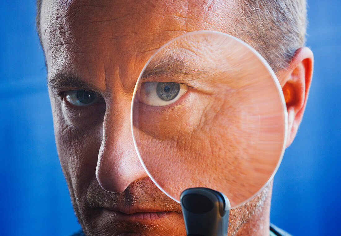 Threatening Looking Man With Magnifying Glass Held Up To Face