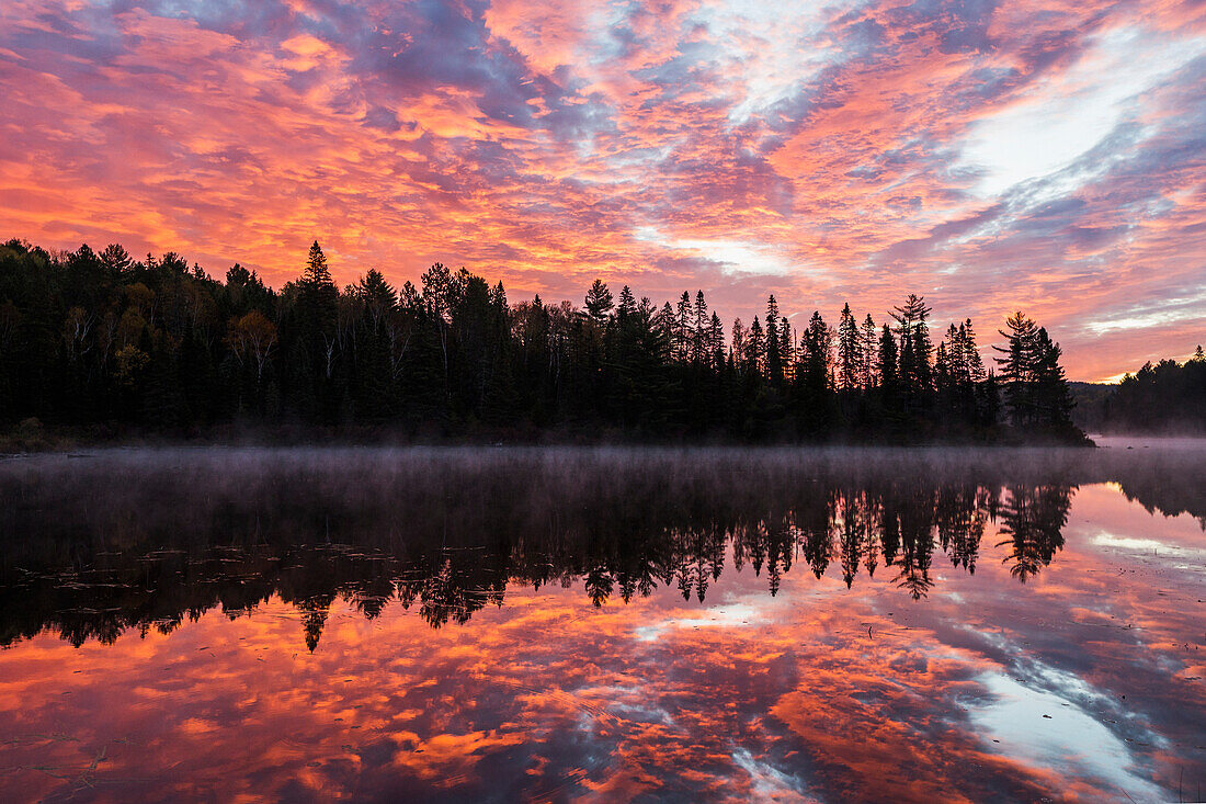 'Red clouds light the sky and water of Costello Lake, Algonquin Park; Ontario, Canada'