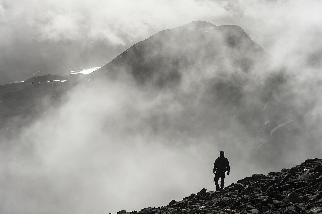 'A man walks out of the clouds from the summit of Maol Chean-dearg; Torridon, Scotland'