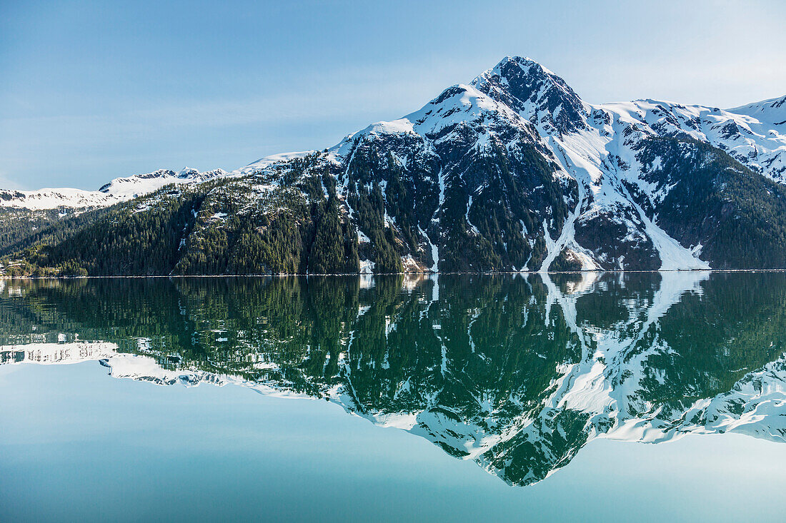'The snow covered Chugach Mountains reflected in the waters of Barry Arm in springtime, Chugach National Forest; Alaska, United States of America'