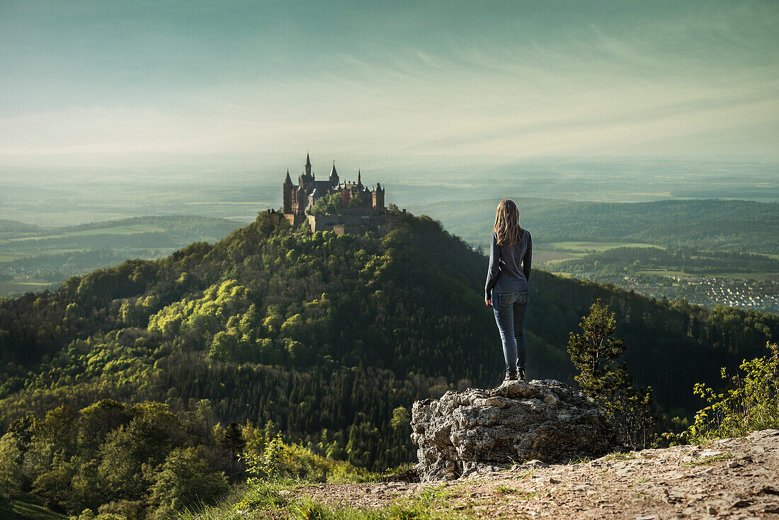 Young woman looking towards Hohenzollern castle from Zeller mountain, Hechingen Bissingen, Swabian Alp, Baden-Wuerttemberg, Germany