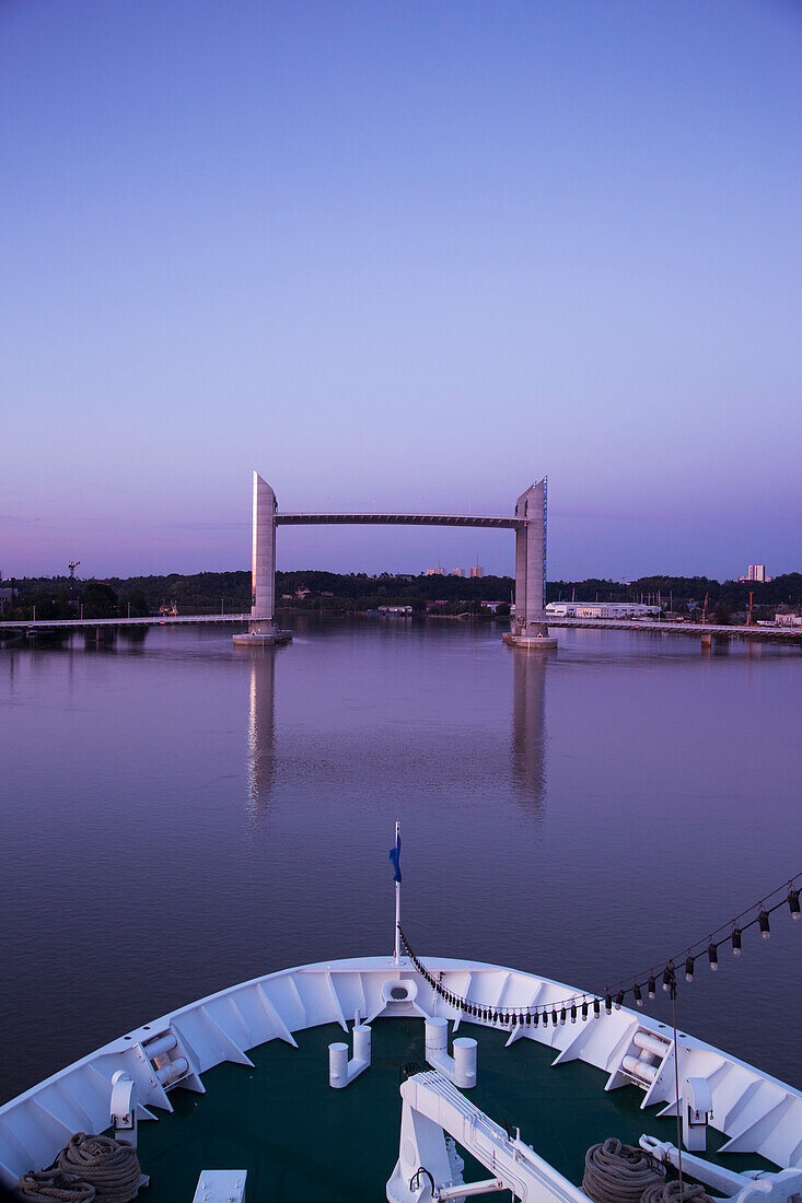 Bow of cruise ship MS Deutschland (Reederei Peter Deilmann) and Pont Jacques Chaban-Delmas lift bridge at dusk, Bordeaux, Gironde, Aquitane, France