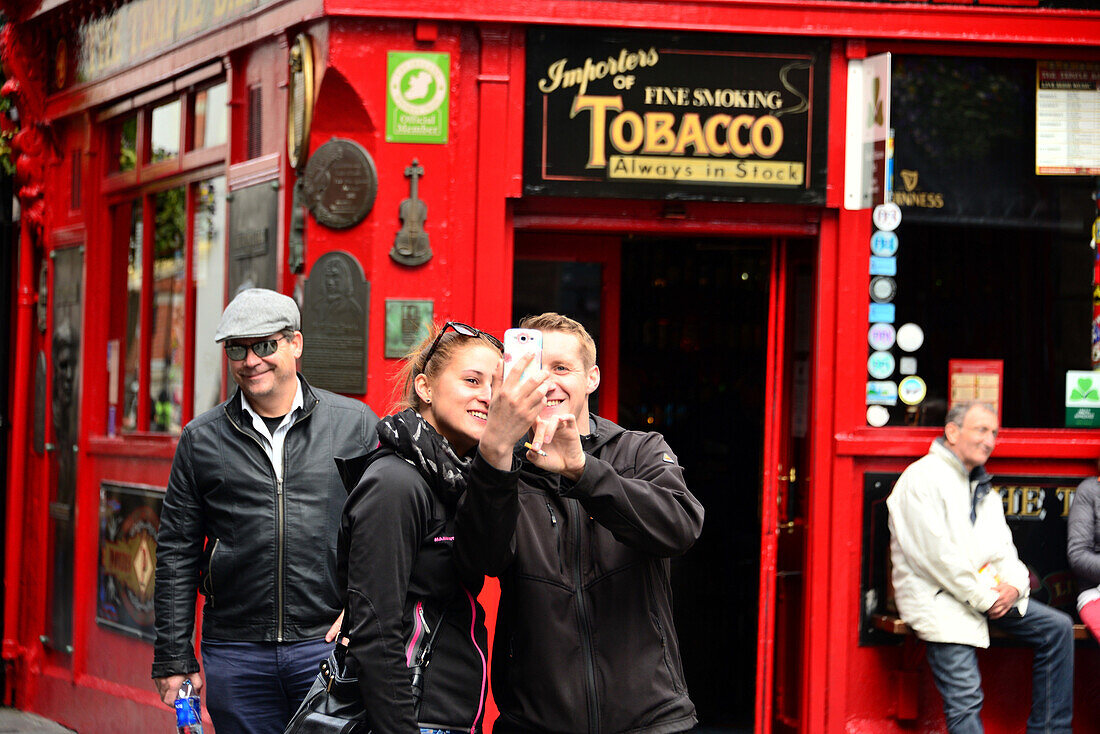 Couple taking a selfie outside a pub in the Temple Bar quarter, Dublin, Ireland