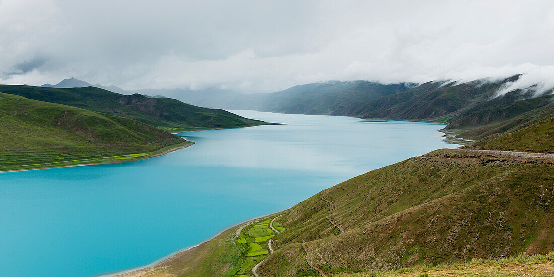 'Hilly and mountainous landscape with sacred lake under a cloudy sky;Shannan xizang china'