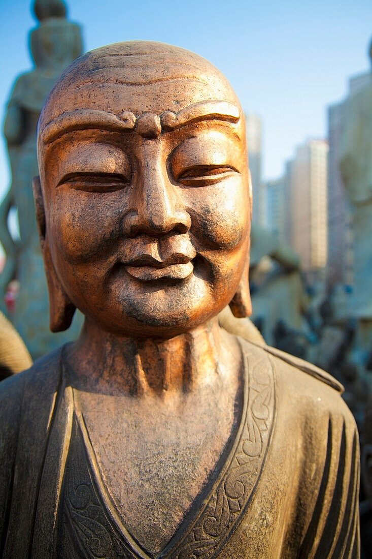 'Bronze faced buddha statue glowing in warm light;Beijing china'