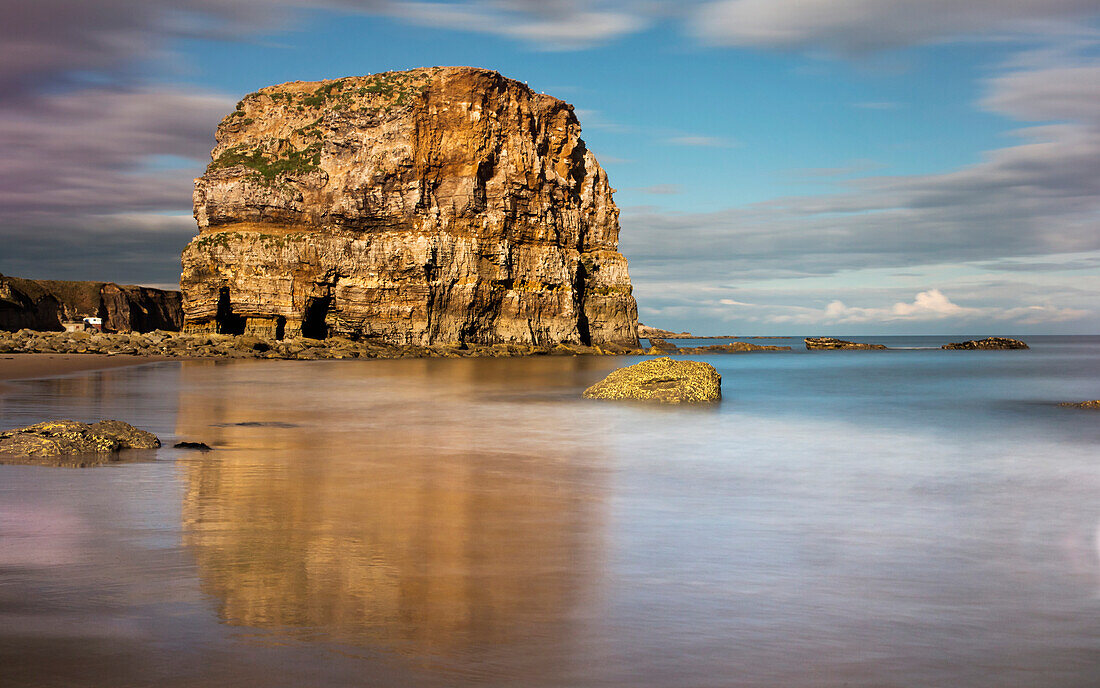 'Large rock formation on the coast reflected in the wet sand;South shields tyne and wear england'