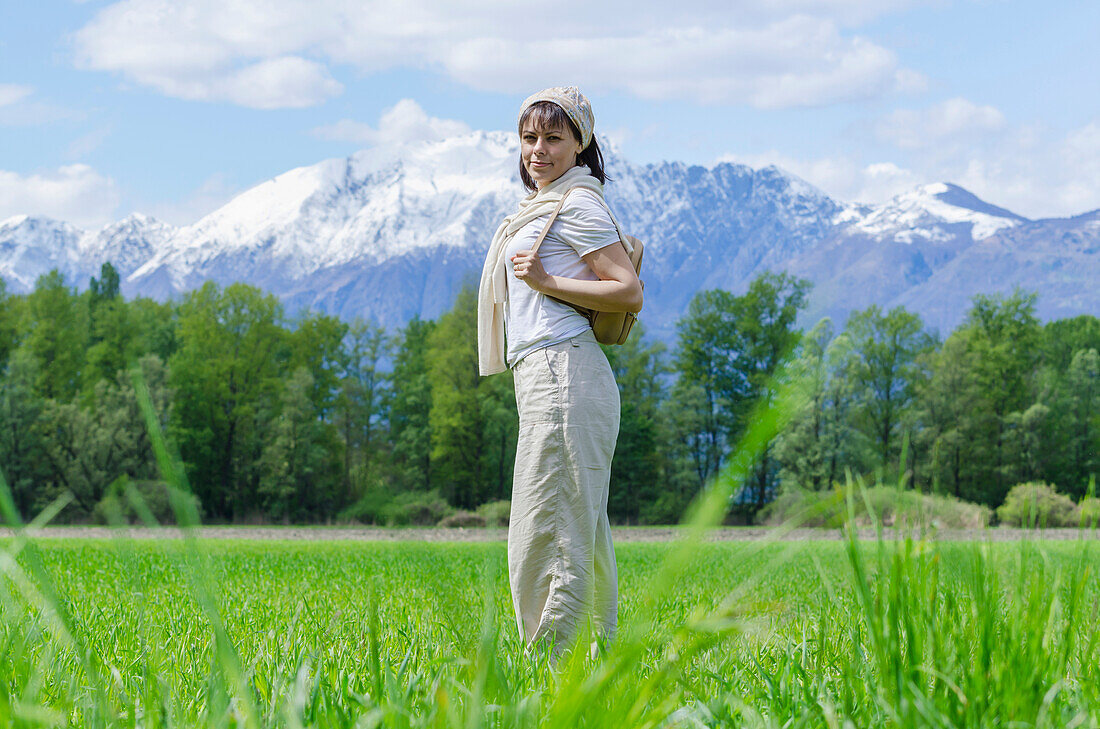 'A woman stands in a grass field with the alps mountain range in the background;Locarno ticino switzerland'