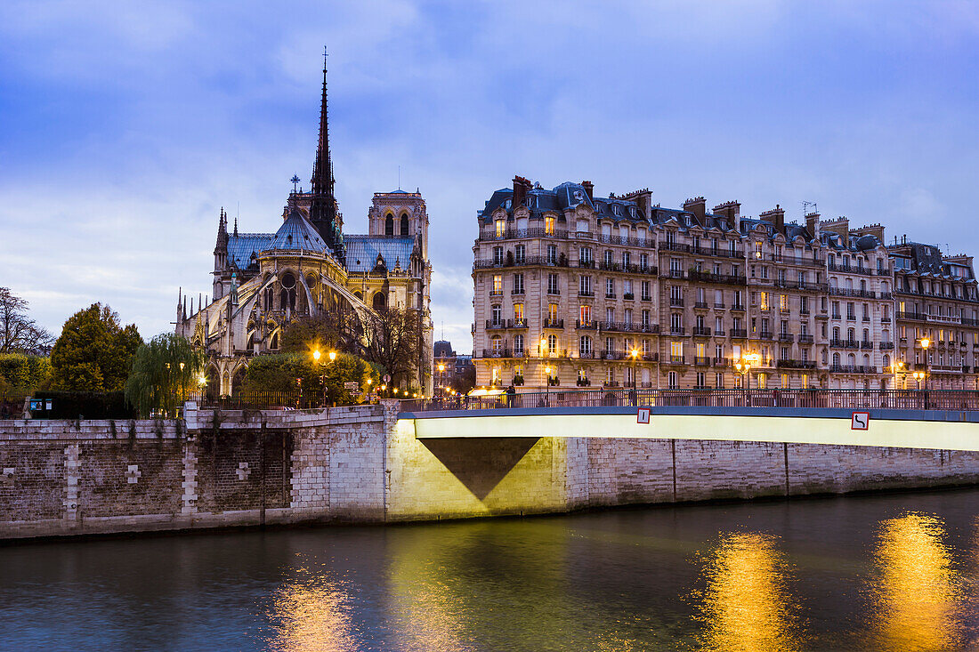A bridge over a river with illuminated lampposts and buildings
