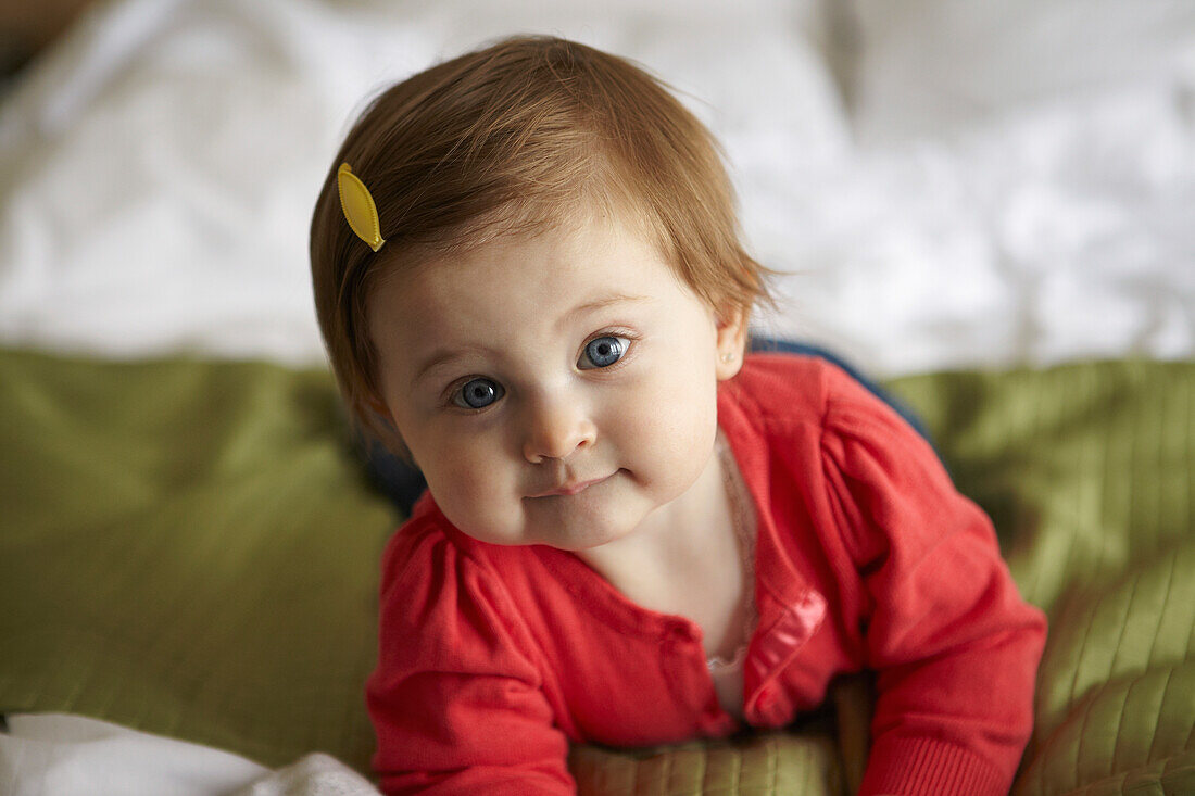 'A Baby Girl Poses For A Portrait While Lying On A Bed; Ottawa, Ontario, Canada'