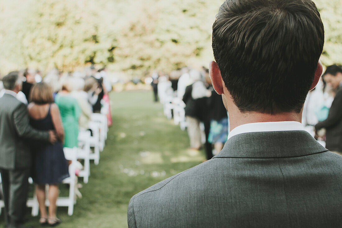 'A Man Standing At The Top Of The Aisle At An Outdoor Wedding; Kirkland, Washington, United States Of America'