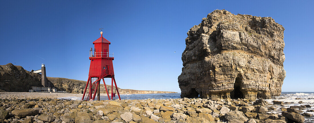 'Groyne lighthouse beside a rock formation along the shoreline; South Shields, Tyne and Wear, England'