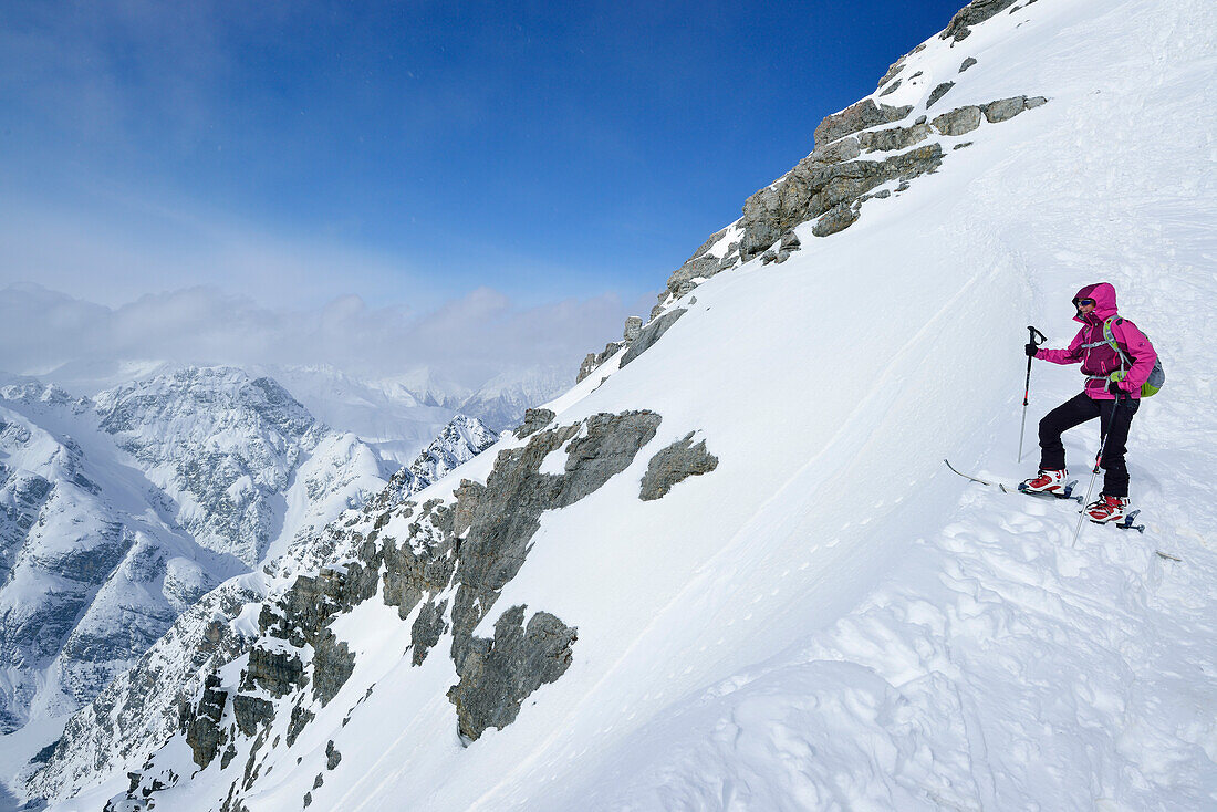 Frau auf Skitour steht in Scharte zwischen Piz Zuort und Piz da la Crappa, Piz Zuort, Sesvennagruppe, Engadin, Graubünden, Schweiz