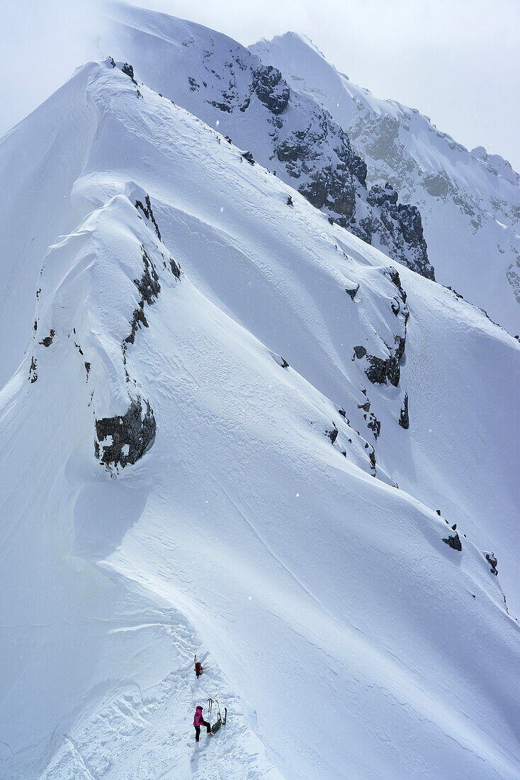 Frau auf Skitour steht in Scharte zwischen Piz Zuort und Piz da la Crappa, Piz Zuort, Sesvennagruppe, Engadin, Graubünden, Schweiz