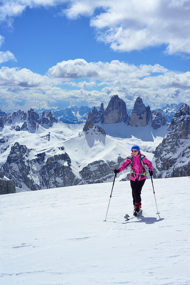 Frau auf Skitour steigt zum Hochebenkofel auf, Paternkofel und Drei Zinnen im Hintergrund, Sextener Dolomiten, Südtirol, Italien