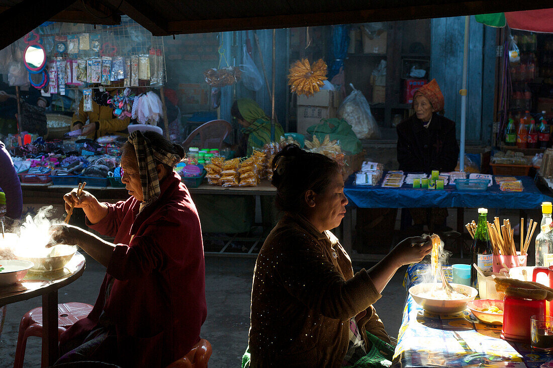 Women eating noodle soup at the market in Kyaing Tong, Kentung, Shan State, Myanmar, Burma