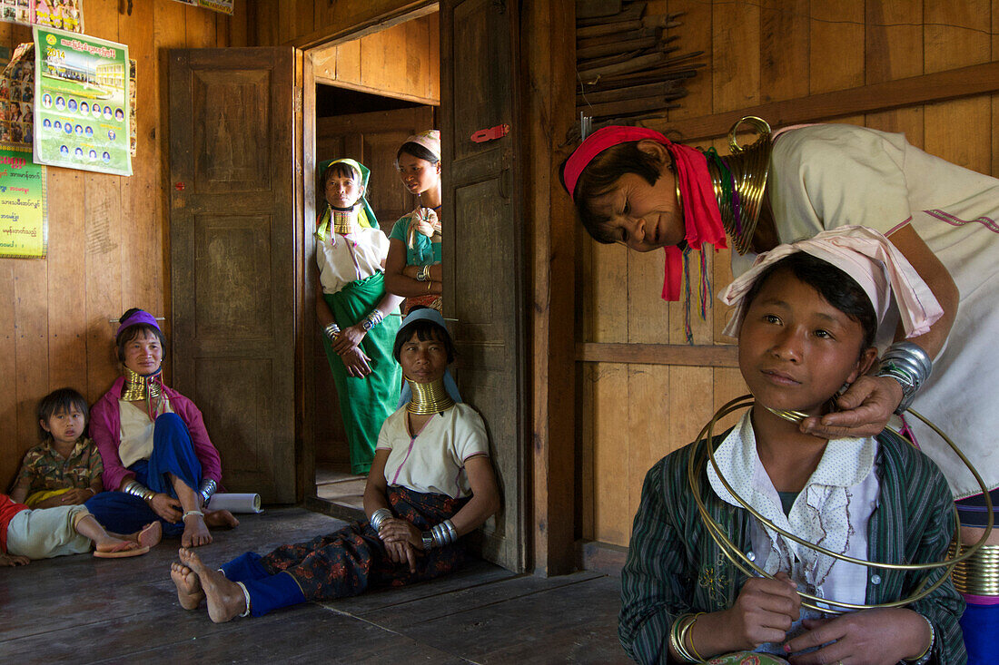 Langhals Frauen mit typischem Halsschmuck, eine 13-jährige Schülerin bekommt auf eigenen Wunsch zum ersten Mal den Halsschmuck angelegt, Padaung Frauen in ihrem Haus bei Loikaw, Kayah Staat, Karenni Staat, Myanmar, Burma, Asien
