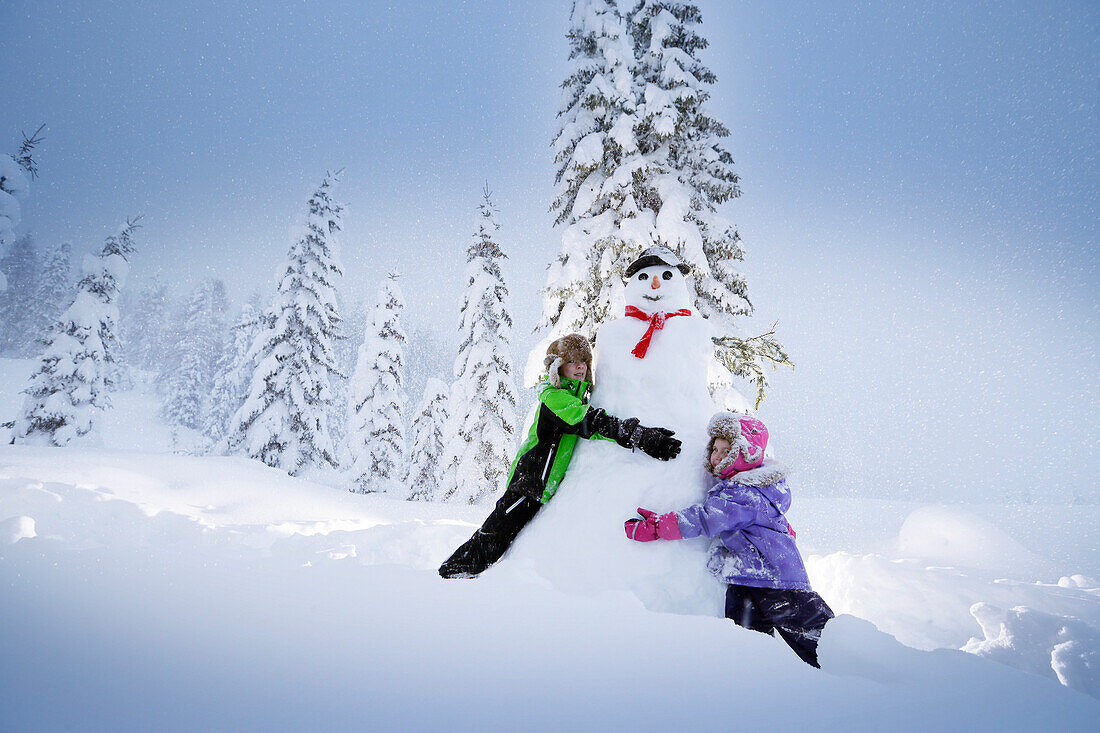 Children embracing a snowman, Passo Monte Croce di Comelico, South Tyrol, Italy