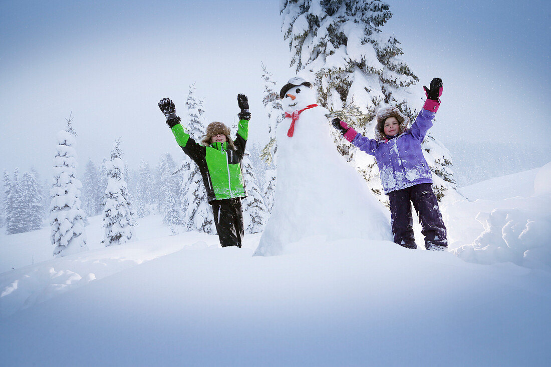 Kinder jubeln neben einem Schneemann, Kreuzbergpass, Südtirol, Italien