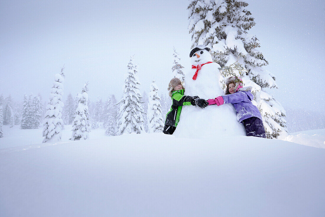 Children embracing a snowman, Passo Monte Croce di Comelico, South Tyrol, Italy