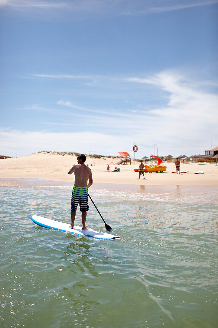 Stand-up Paddler nahe Water Sports Centre am Strand von Martinhal, Martinhal Beach Sagres, Algarve, Atlantikküste, Portugal, Südwestende Europas