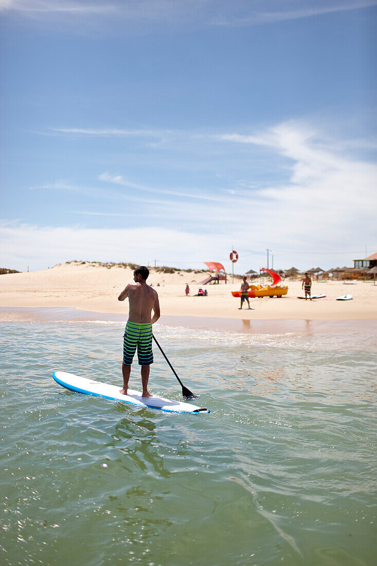 Stand-up paddler near Water Sports Centre, Martinhal Beach, Sagres, Algarve, Portugal, southernmost region of mainland Europe