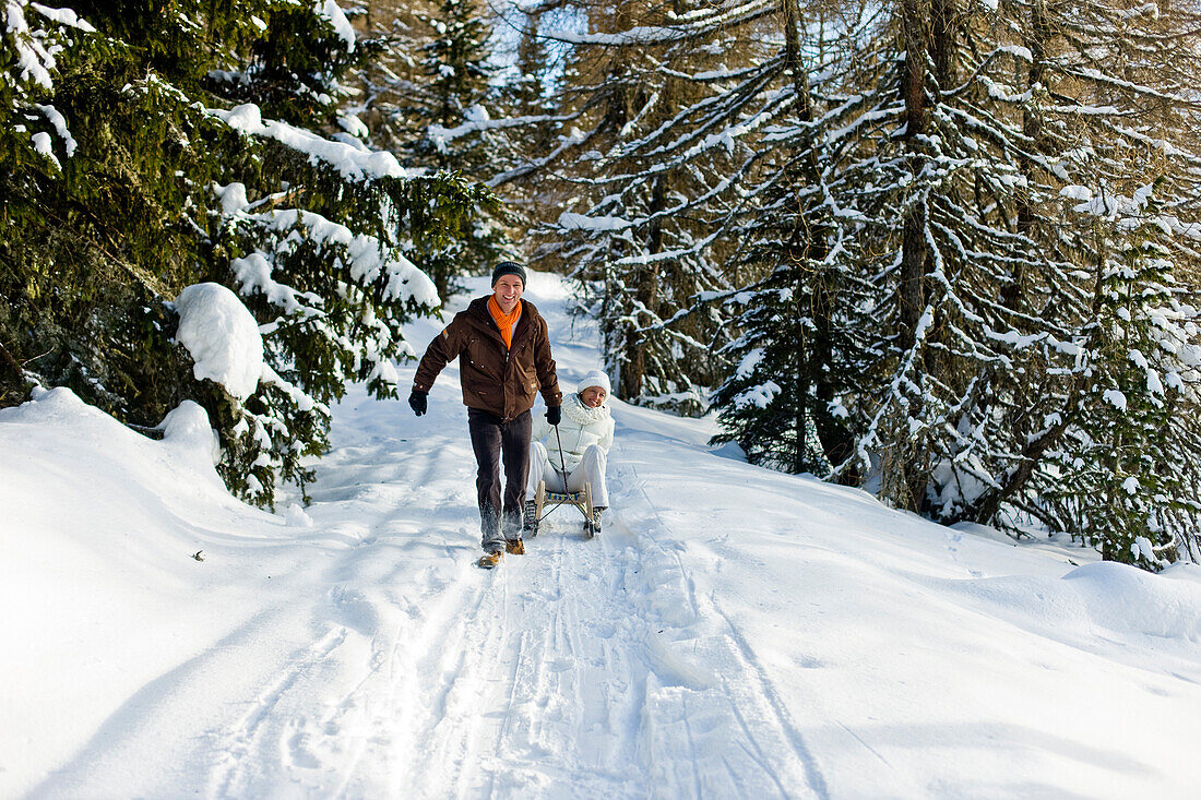 Mann zieht Frau auf einem Schlitten, Mühlen, Steiermark, Österreich