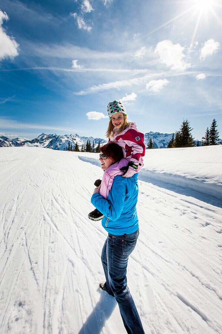 Woman giving girl a piggyback ride, Planai, Schladming, Styria, Austria