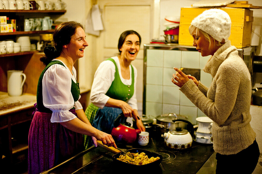 Women preparing Kaiserschmarrn, young woman tasting it, Austria